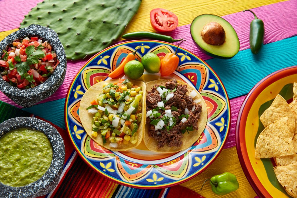 Tacos mexicanos autênticos com guacamole e pico de gallo, servidos em um prato colorido.