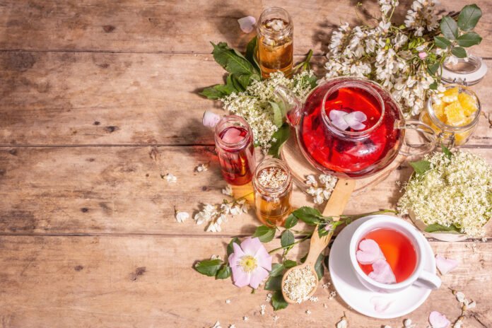 Chás e infusões aromáticas com flores e ervas em mesa de madeira