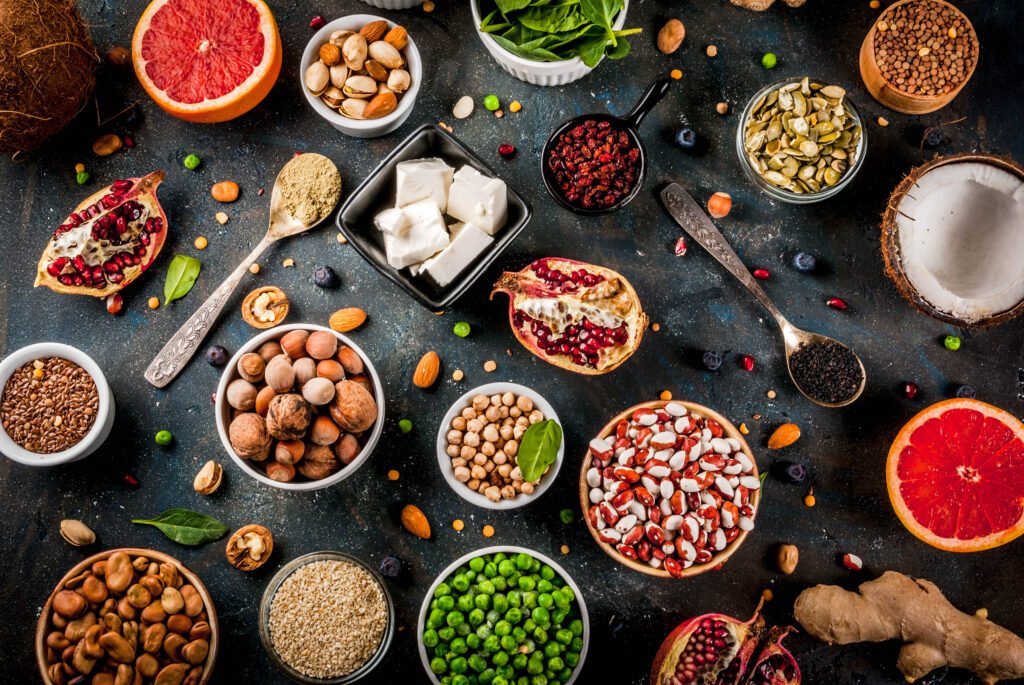 Superfoods dispostas em uma mesa rústica, incluindo romãs, sementes, nozes, legumes, ervas e coco, representando uma dieta saudável.