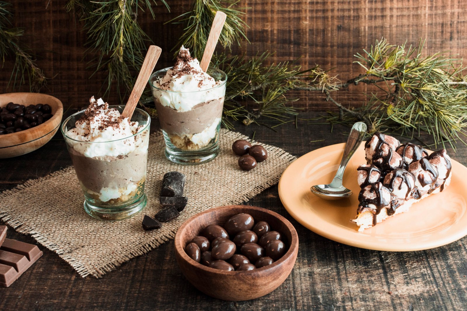 Taças de sobremesa gelada de chocolate com chantilly e fatia de torta de chocolate em ambiente rústico