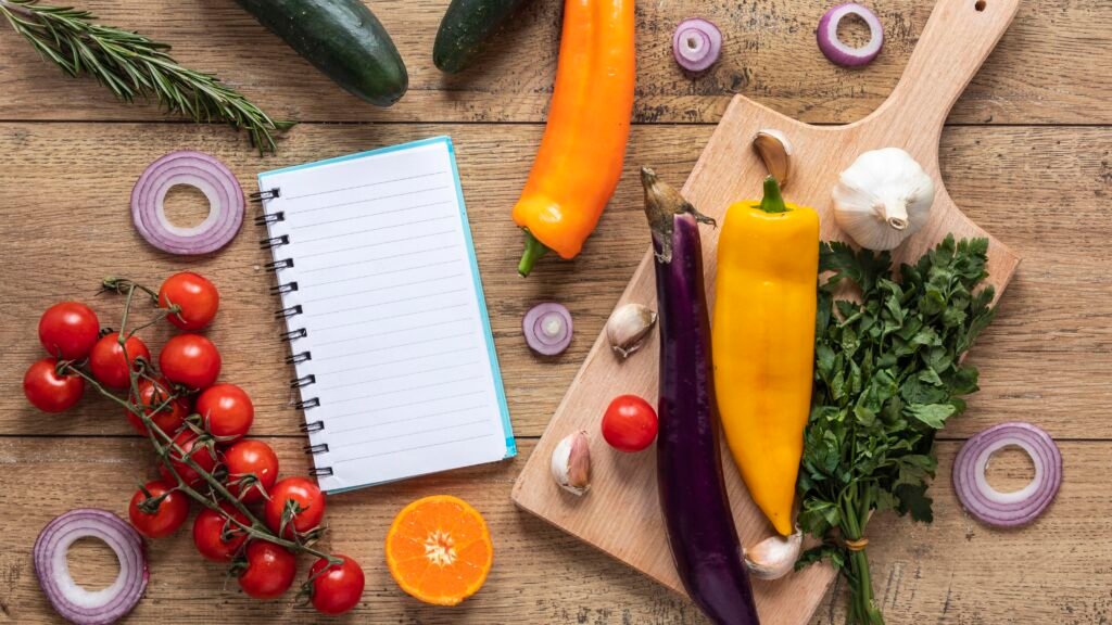 Ingredientes frescos para receitas funcionais ao lado de um caderno em branco em uma mesa de madeira.