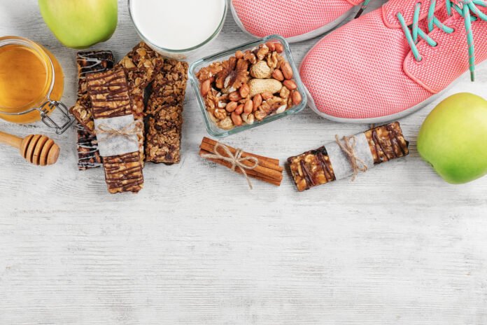 Doces saudáveis como barrinhas de cereais, mel, nozes, maçãs verdes e canela ao lado de tênis esportivo, representando equilíbrio entre saúde e sabor.