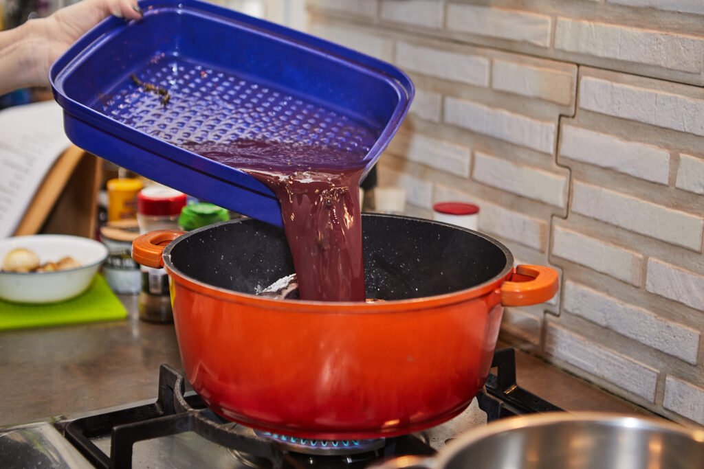 Líquido sendo vertido em panela para preparo de redução culinária