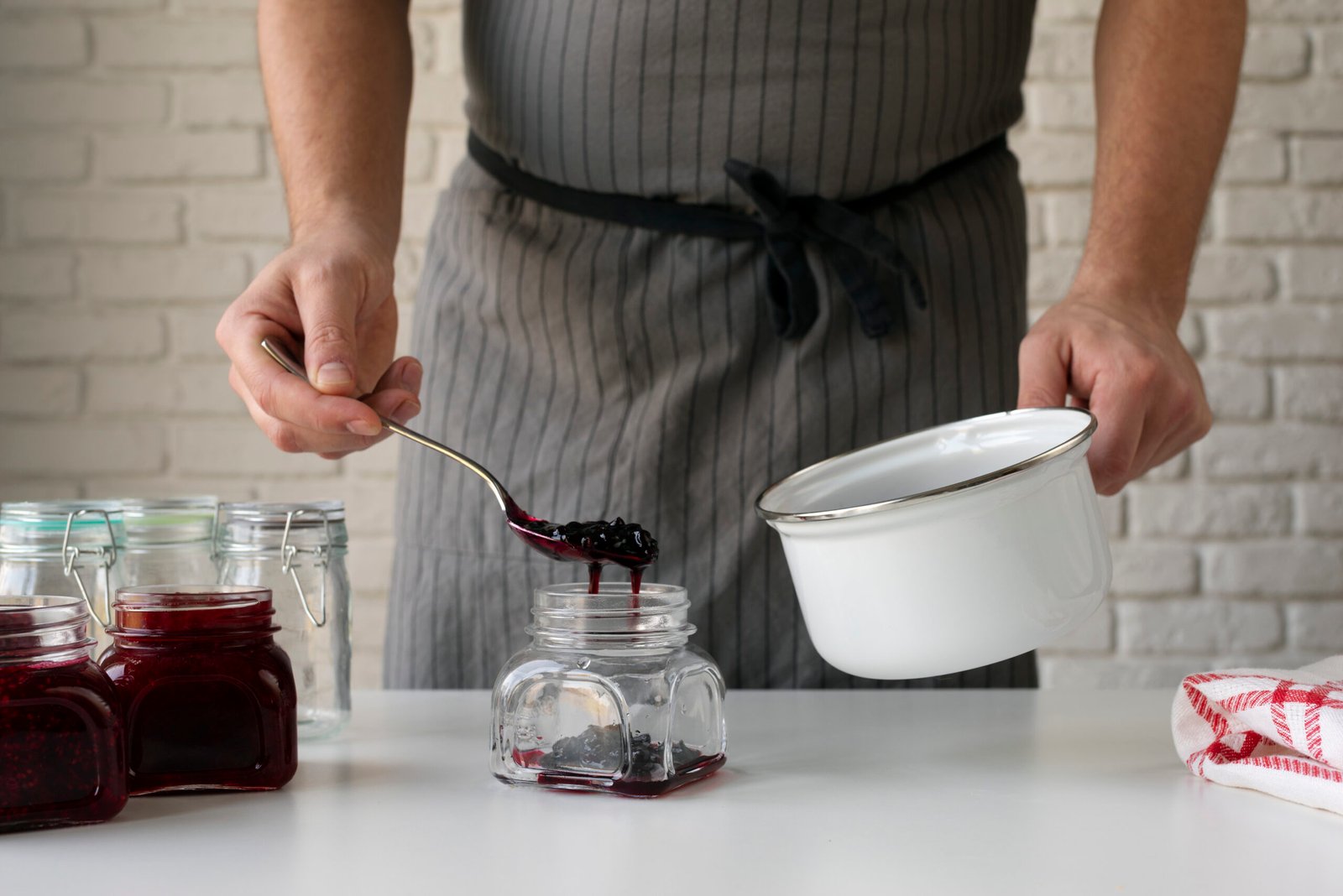 Chef preparando redução de frutas vermelhas em potes de vidro para molhos intensos