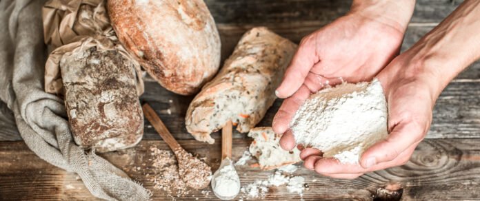 Pães artesanais com farinha e fermentação caseira sobre uma mesa rústica