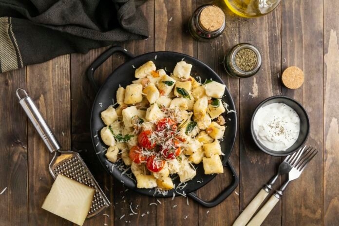 Prato de gnocchi italiano artesanal servido com tomates cereja e queijo ralado.