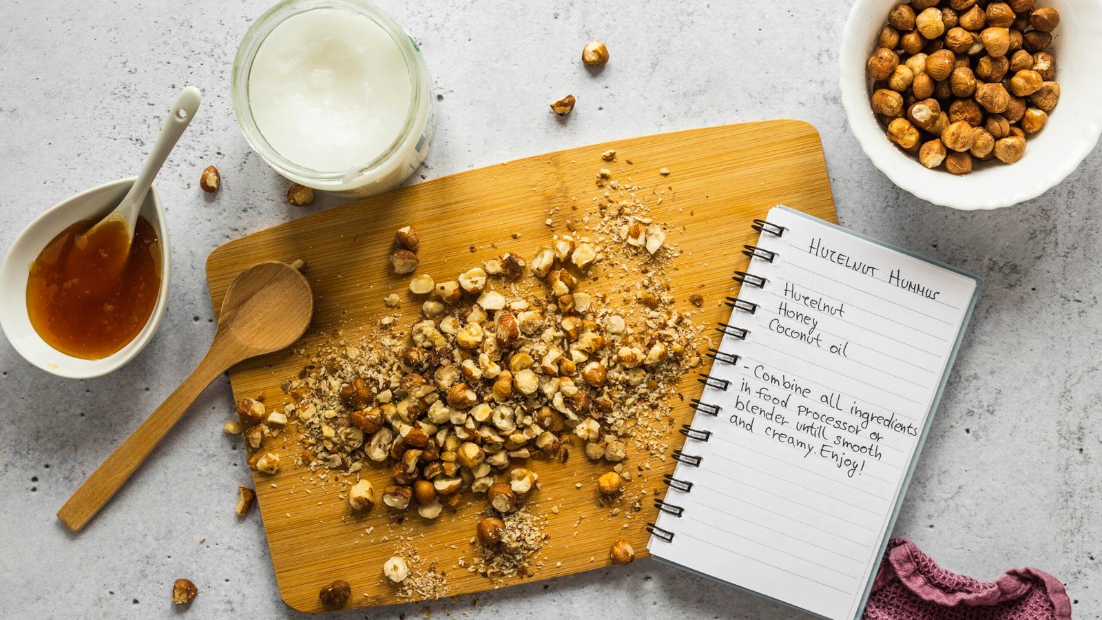 Ingredientes naturais como avelãs, mel e óleo de coco sobre uma tábua, representando opções saudáveis para substituições.