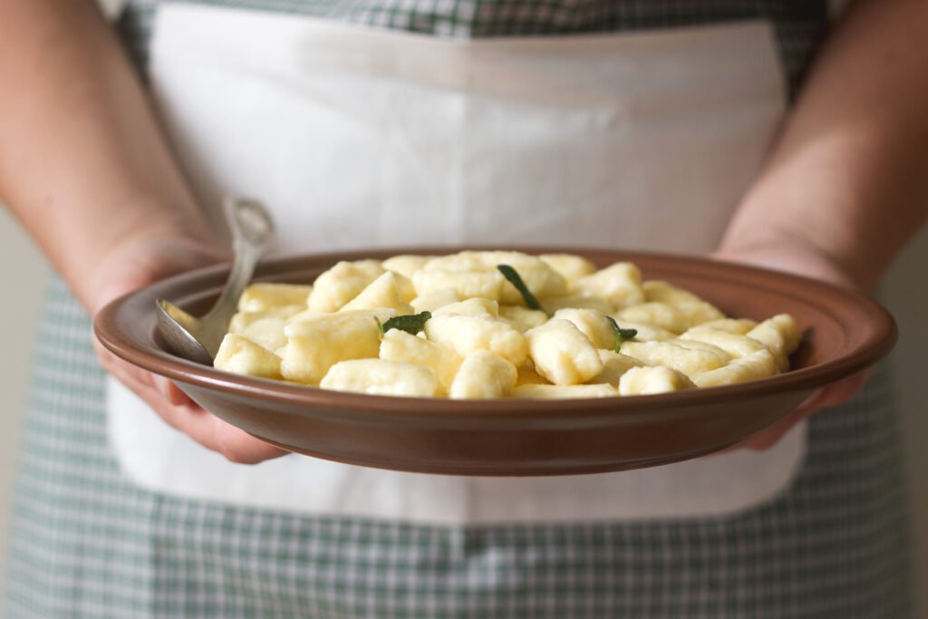 Prato de gnocchi italiano artesanal servido em uma travessa de cerâmica.