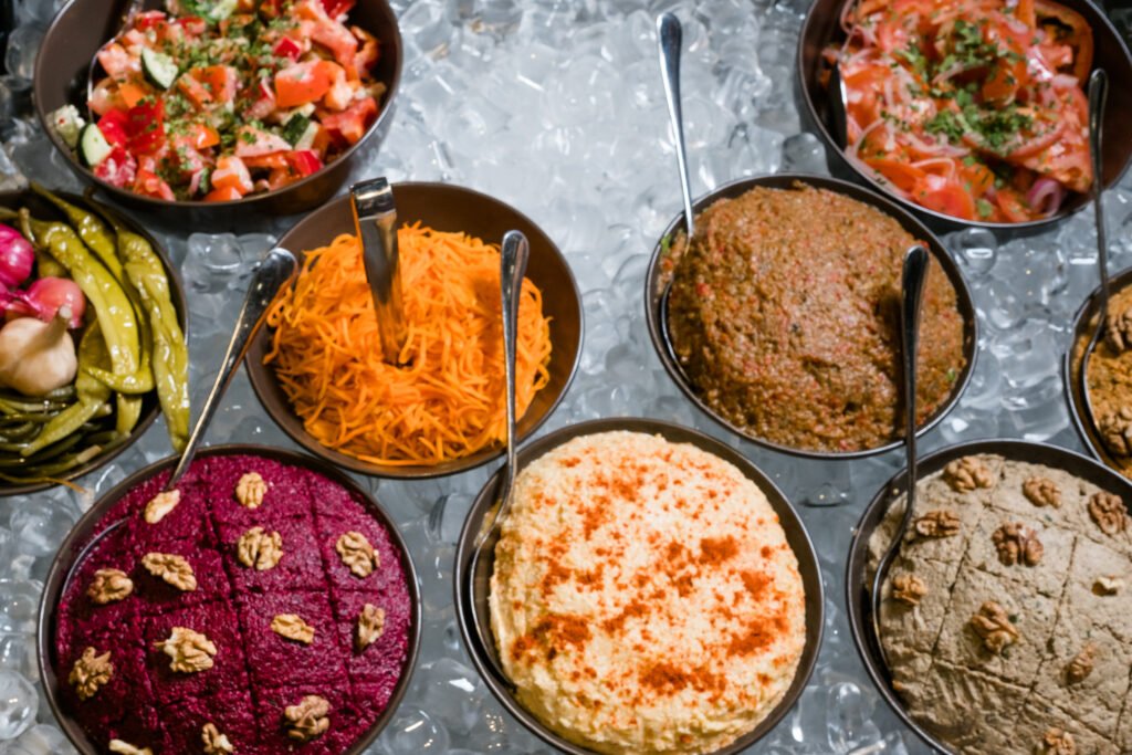 Pratos tradicionais da cozinha árabe dispostos em tigelas, incluindo homus, babaganoush, saladas e pastas temperadas.