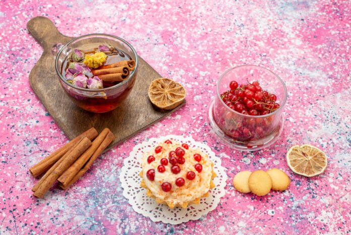 Sobremesas com infusões de chás e ervas ao lado de frutas vermelhas e biscoitos em uma apresentação criativa.