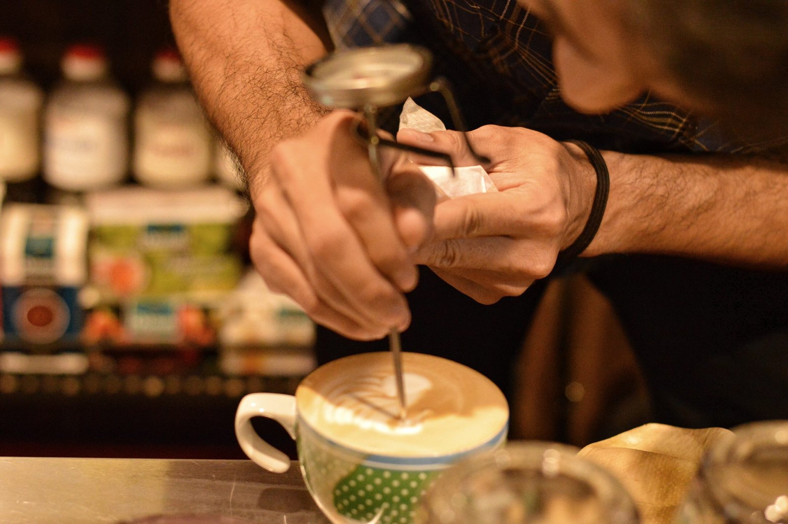 Barista decorando a superfície de um latte artesanal com um desenho em espuma de leite.