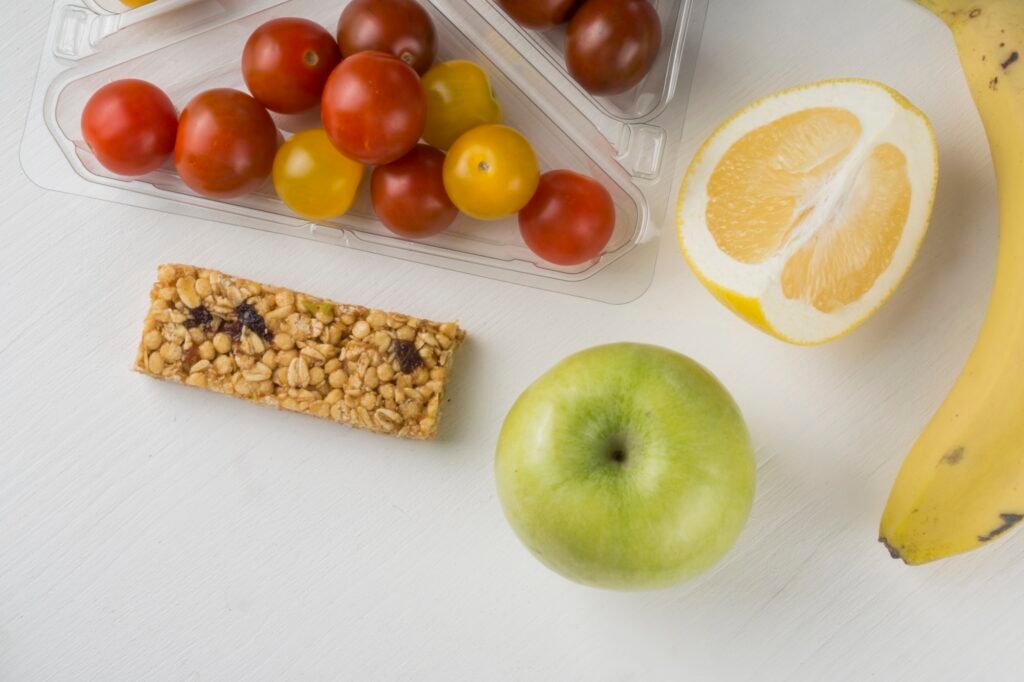 Frutas frescas, barras de cereais e tomates coloridos, opções saudáveis de snacks funcionais.